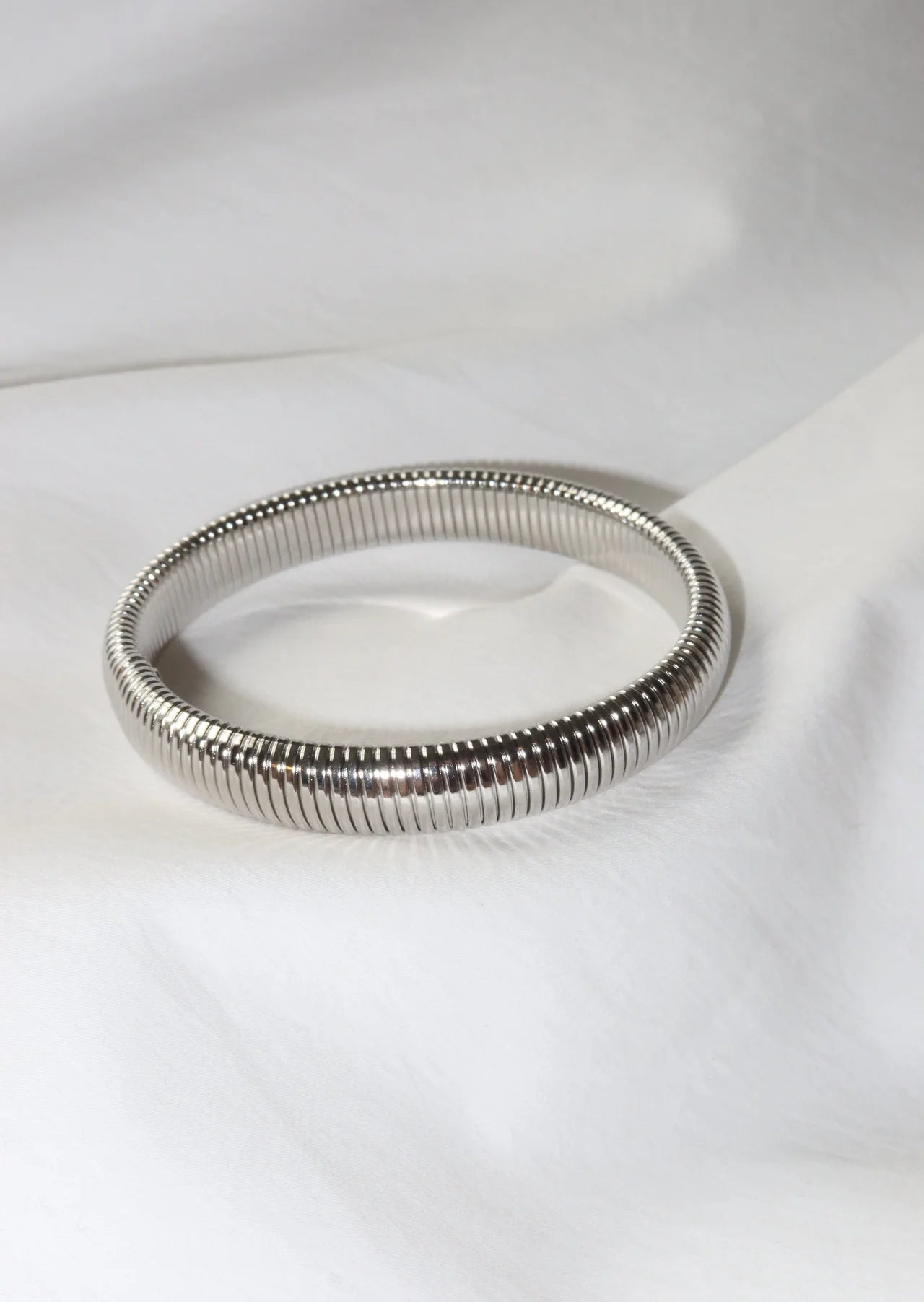 Silver bangle on a white fabric background