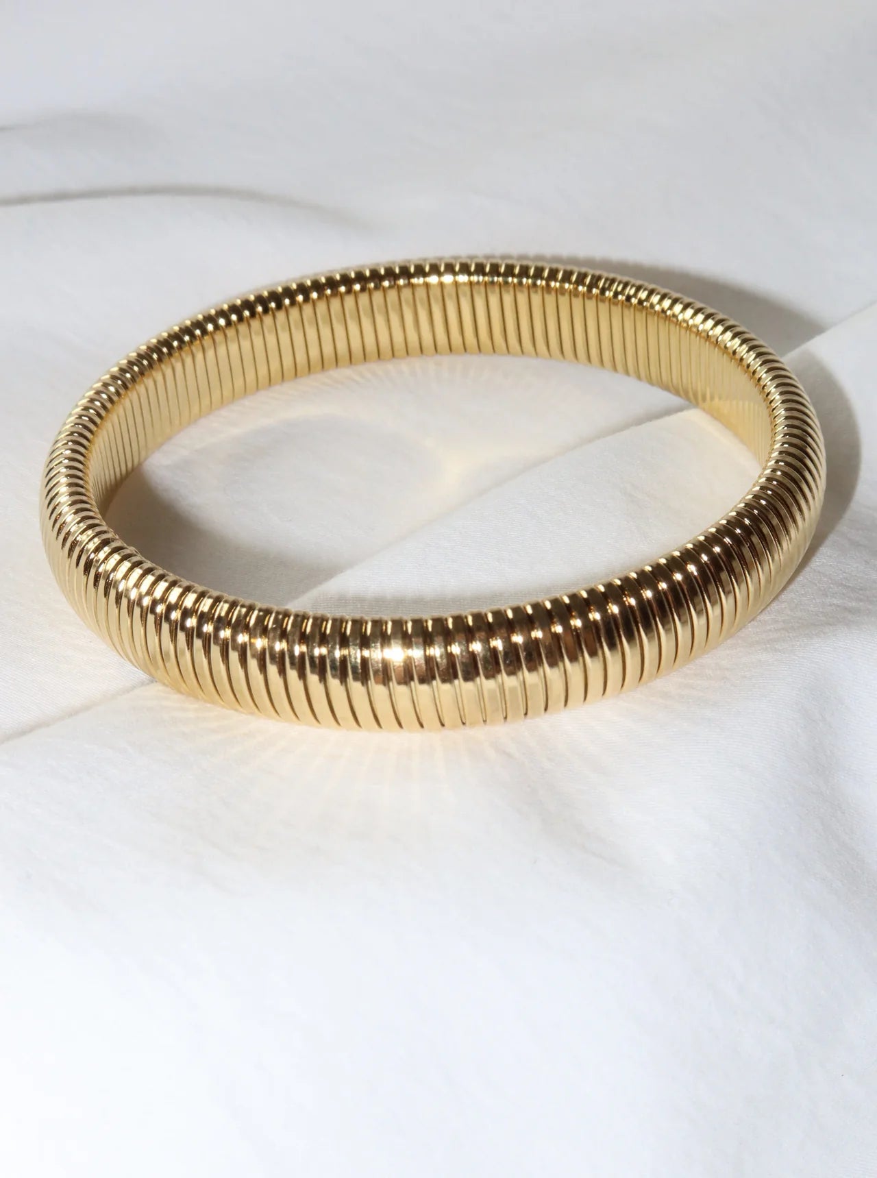 Gold bangle on a white surface