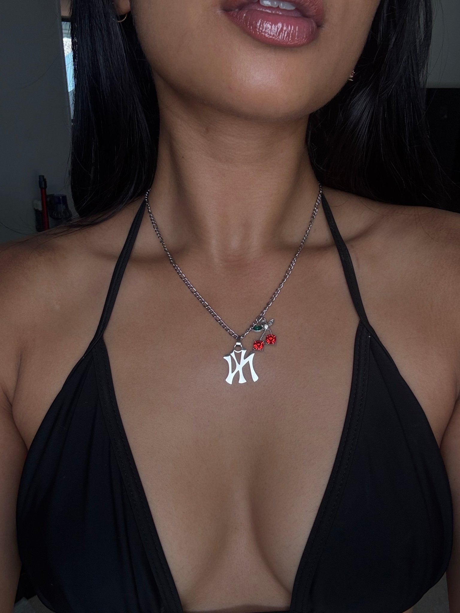 Woman wearing a black top and a necklace with a pendant.
