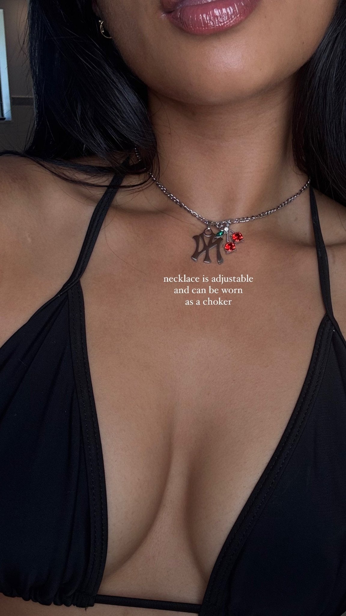 Necklace with charms worn by a person in a black top, with text indicating adjustable length.