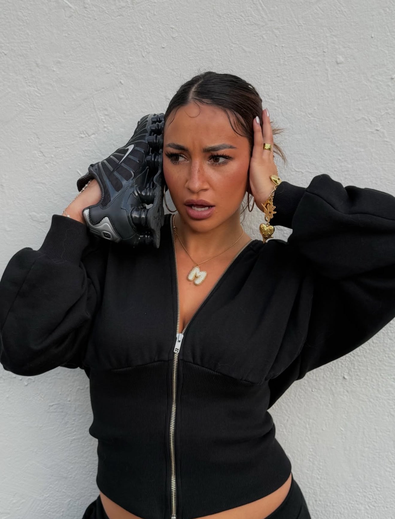 Woman wearing a black outfit against a white wall