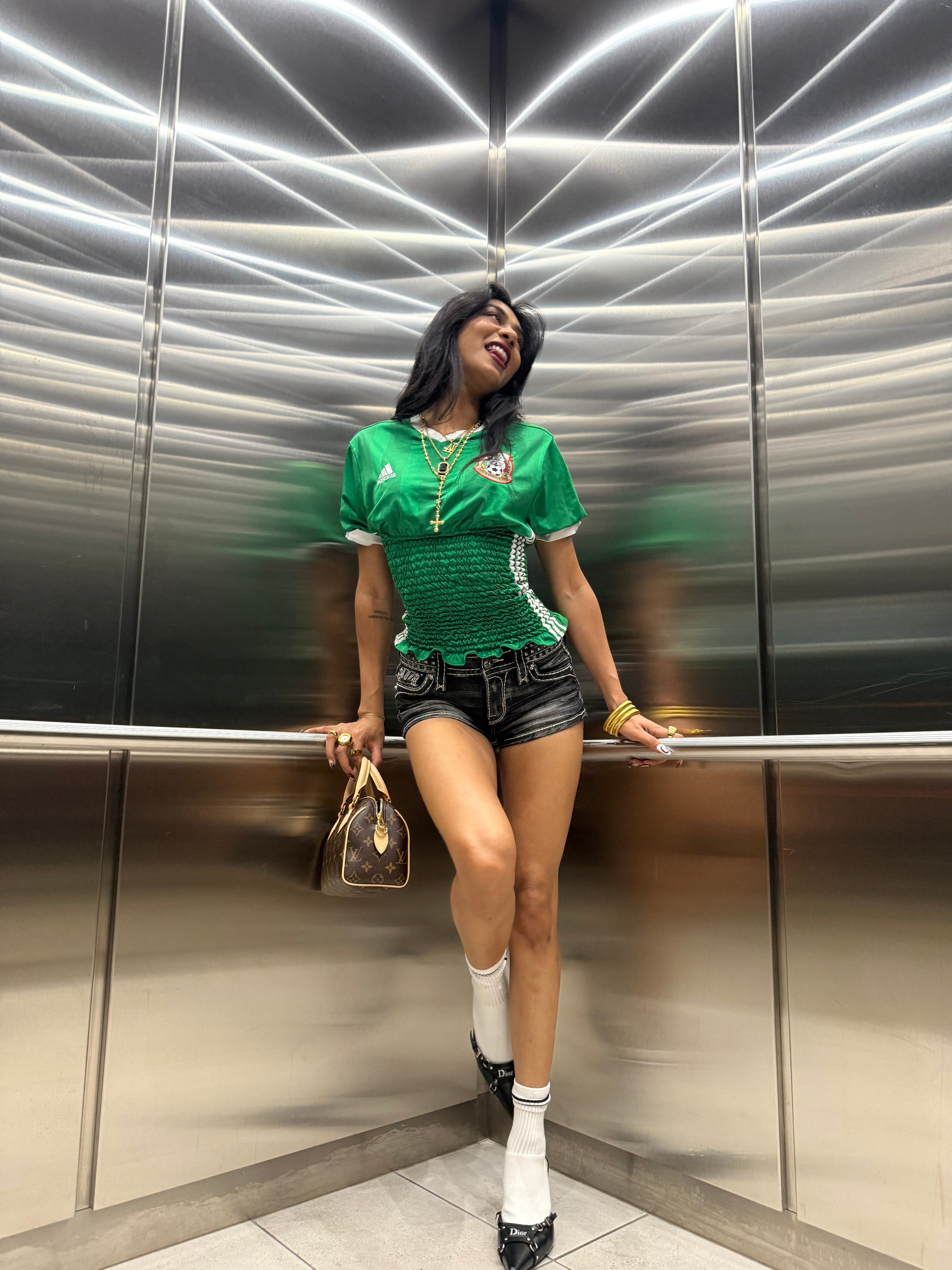Person posing in an elevator with purse