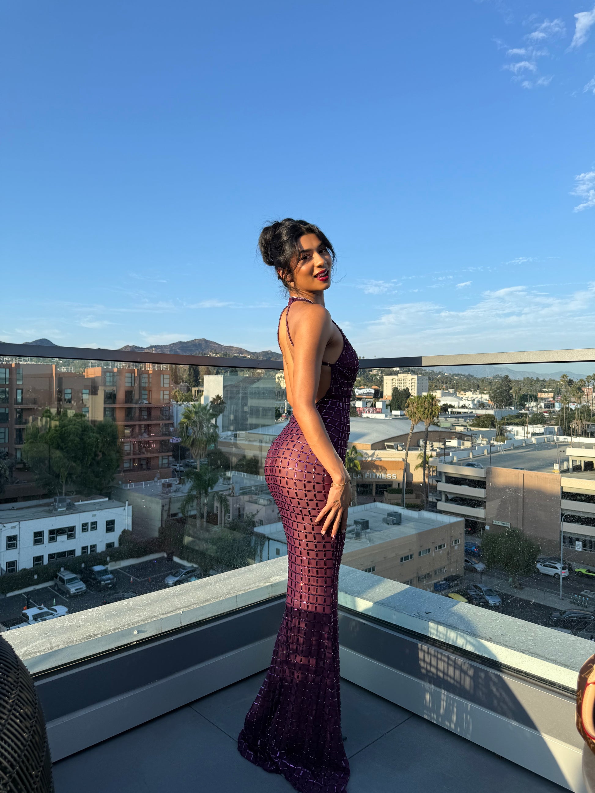 Person in a purple dress standing on a rooftop with a cityscape view