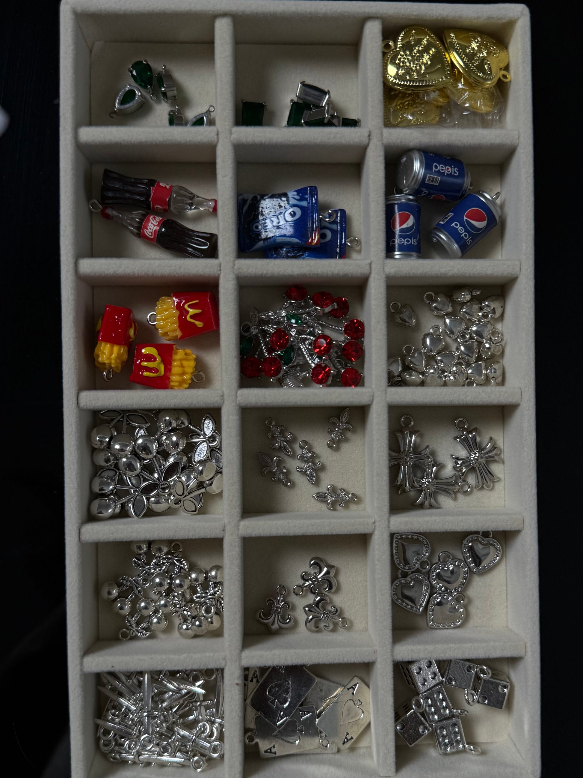 Collection of various small metal charms in a display case.